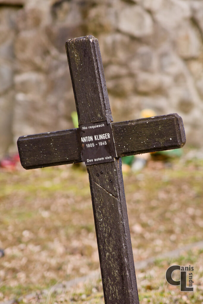 Zbliżenie na krzyż łaciński postawiony najprawdopodobniej w miejscu pochówku żołnierza z II Wojny Światowej. Napis na tabliczce oznacza: Tu spoczywa Anton Klinger 1905-1945 Bóg Żyje