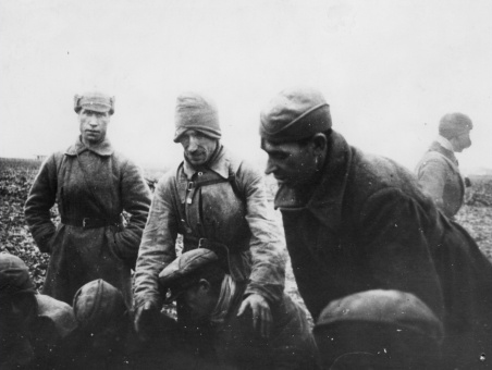 Część jeńców siedzi na ziemi, czterech ubranych w zimowe szynele, względnie pochyla się. Pierwszy stojący z lewej ma na głowie tzw. „budionnówkę”(„szłom”), drugi naciągniętą na uszy furażerkę, czwarty czapkę „uszankę” z opuszczonymi nausznikami. [źródło: IPN Rz 19/172]